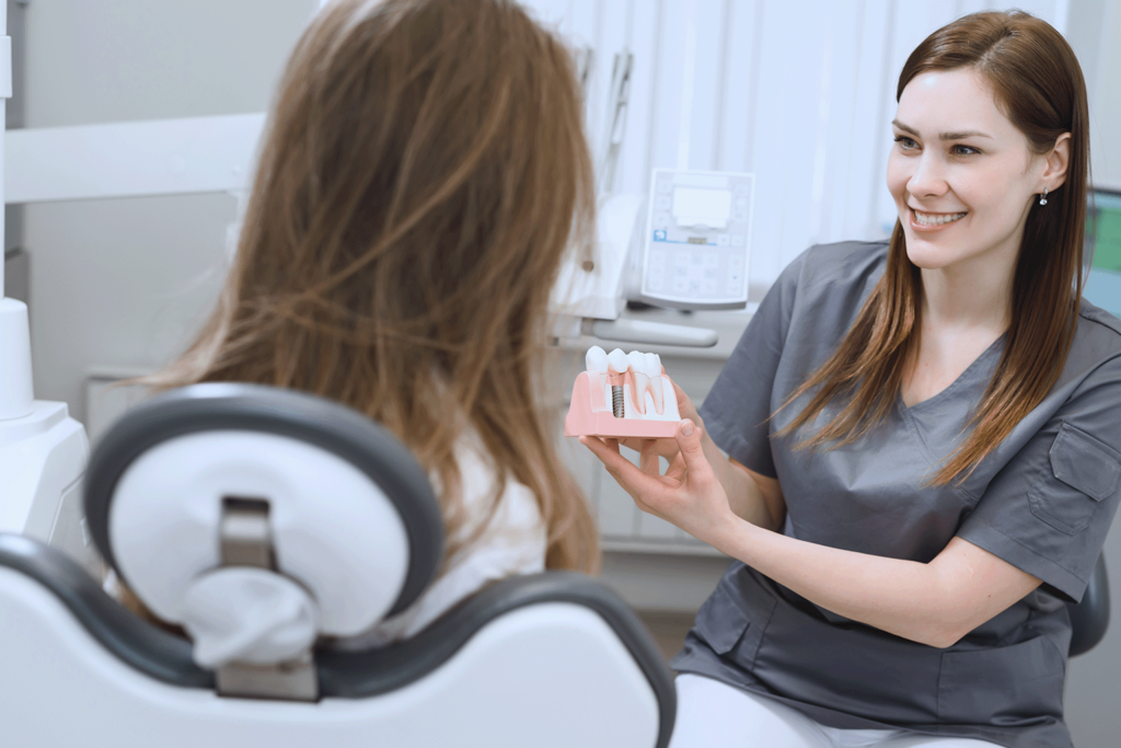 patient looking at implant model in dentist's hands