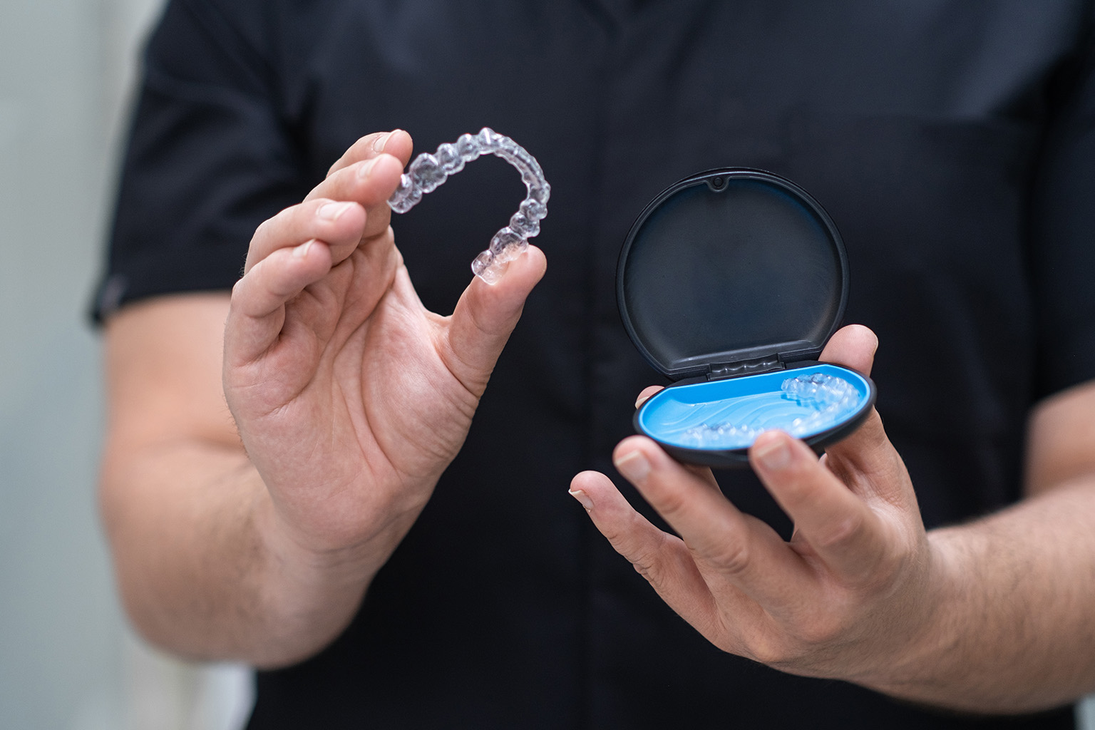 hands holding clear aligners and case