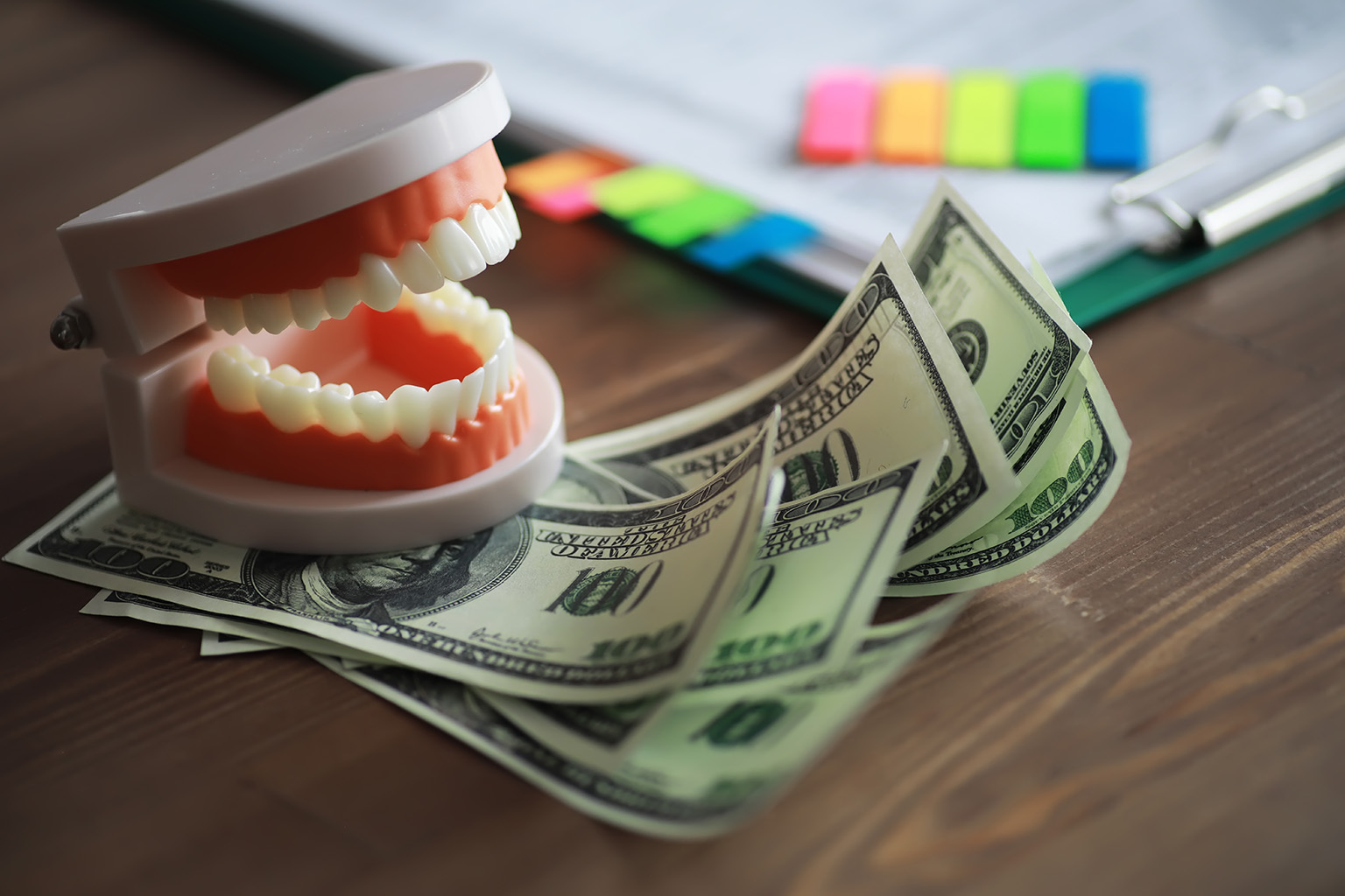 model of teeth sitting on a stack of paper money