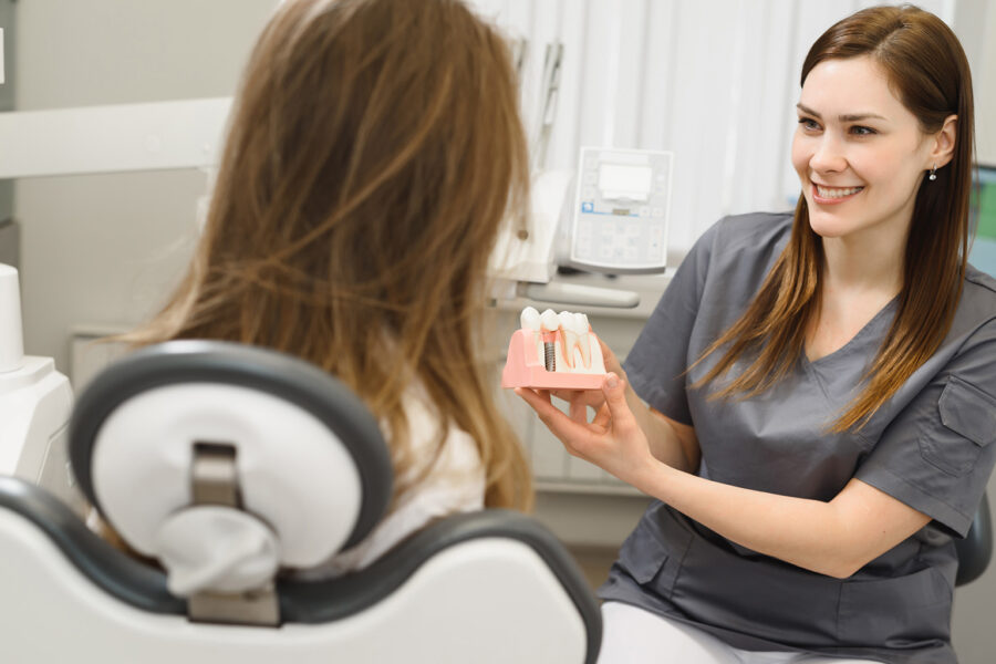 dentist showing patient mouth model with a dental implant