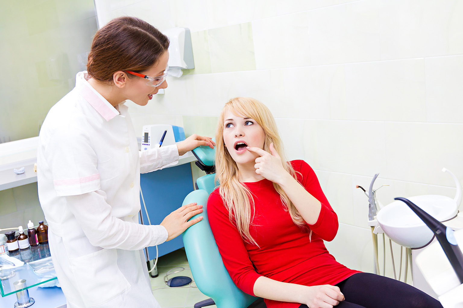 dentist talking to patient that is pointing to her own mouth