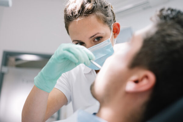female dentist using dental tool in male patient's mouth