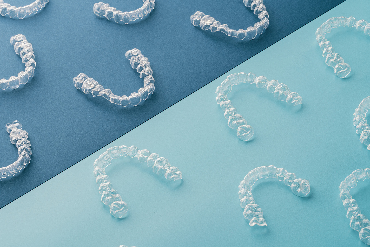 many clear aligners laying on a blue surface
