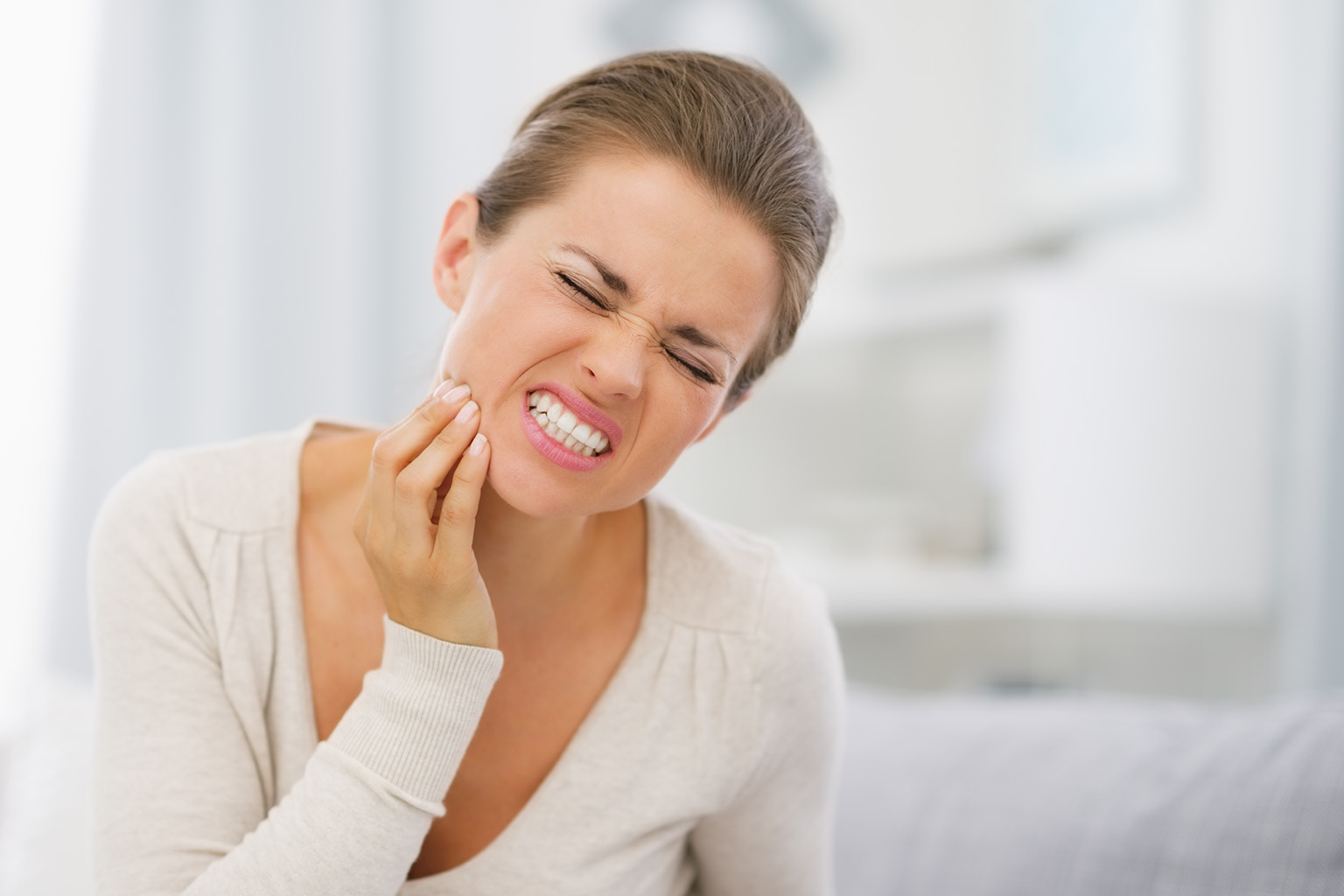 woman holding her jaw in pain