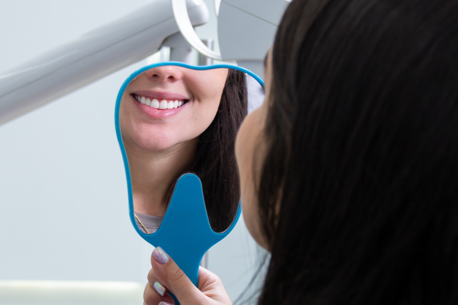 woman smiling into hand mirror