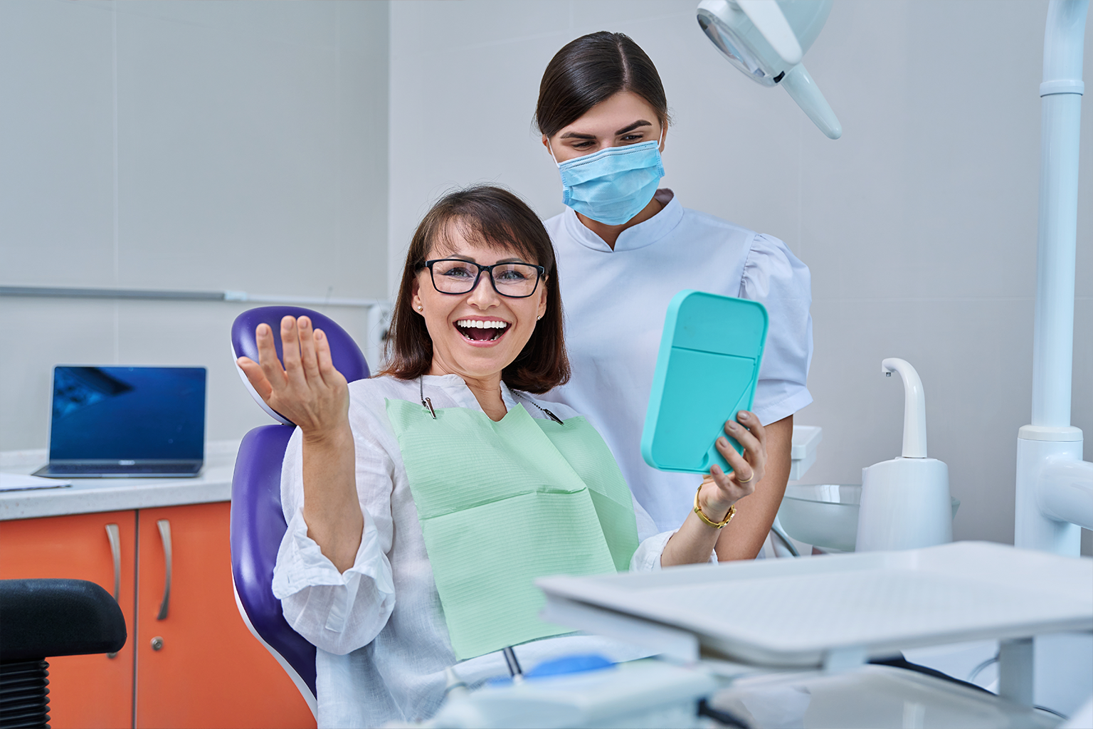 woman smiling in dental chair with dentist behind her