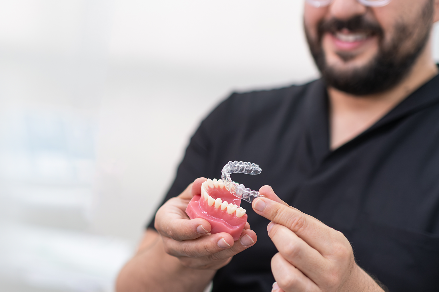 man placing clear aligner on teeth model