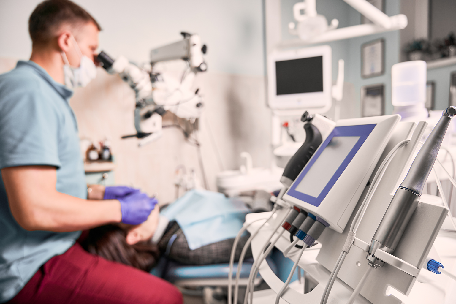 dentist looking into magnifier at patient's teeth in dental chair