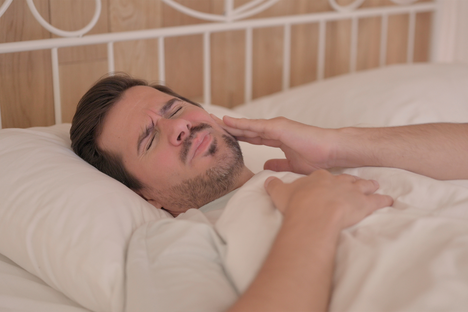 man holding cheek in pain in bed