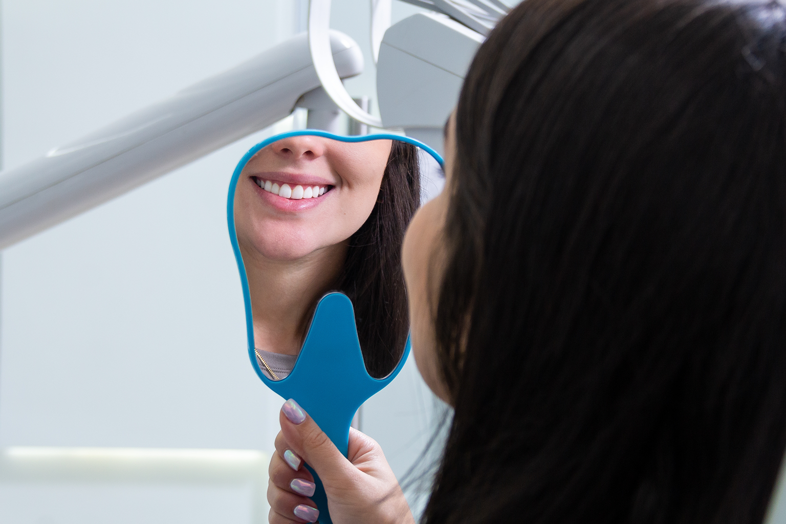 woman smiling into hand mirror