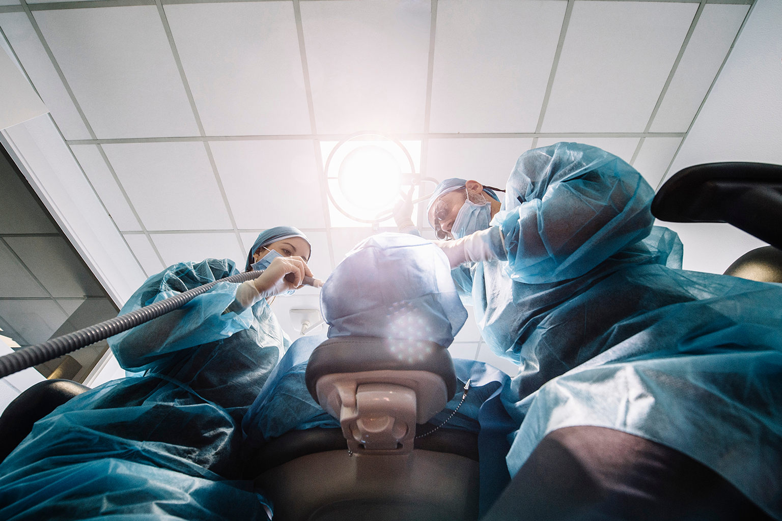 back of patient's head with dental staff standing over them