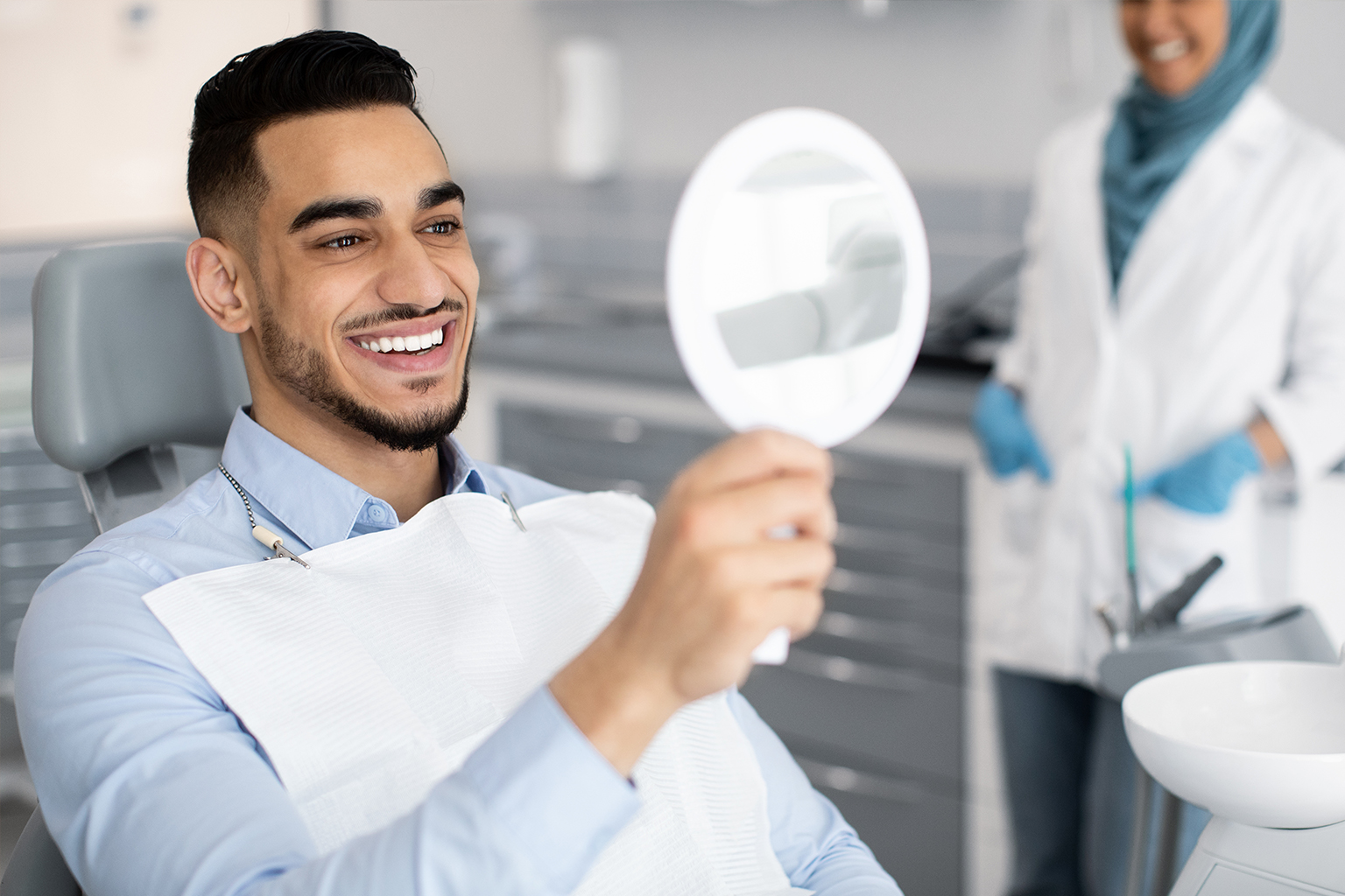 man smiling into handheld mirror