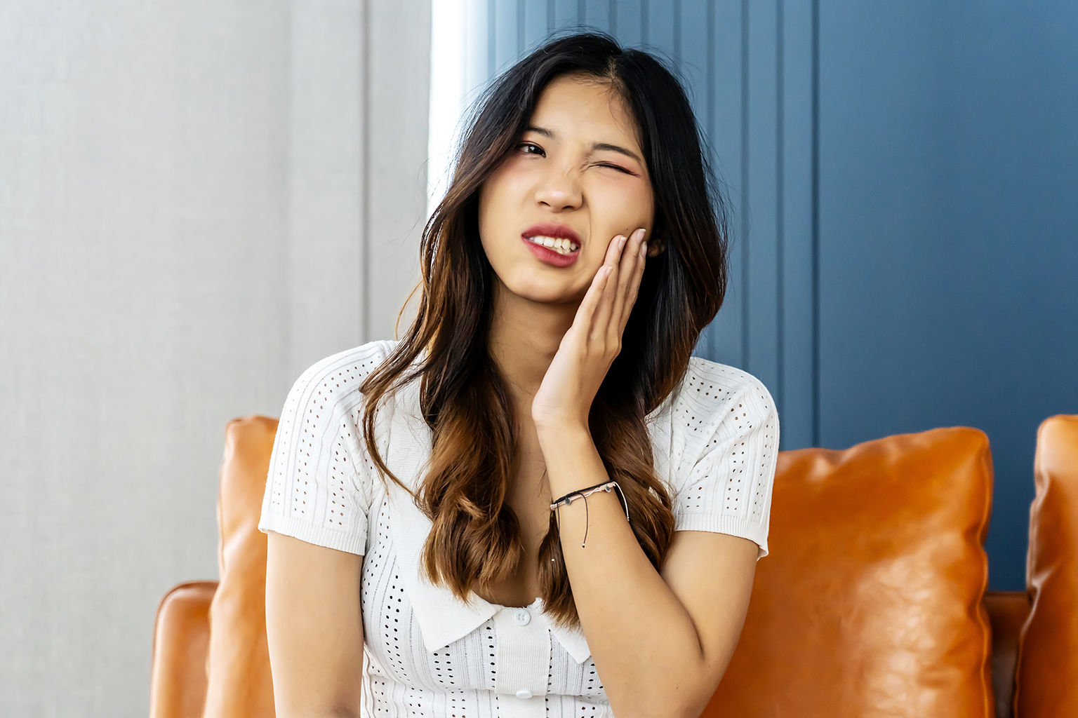 woman holding her cheek in pain