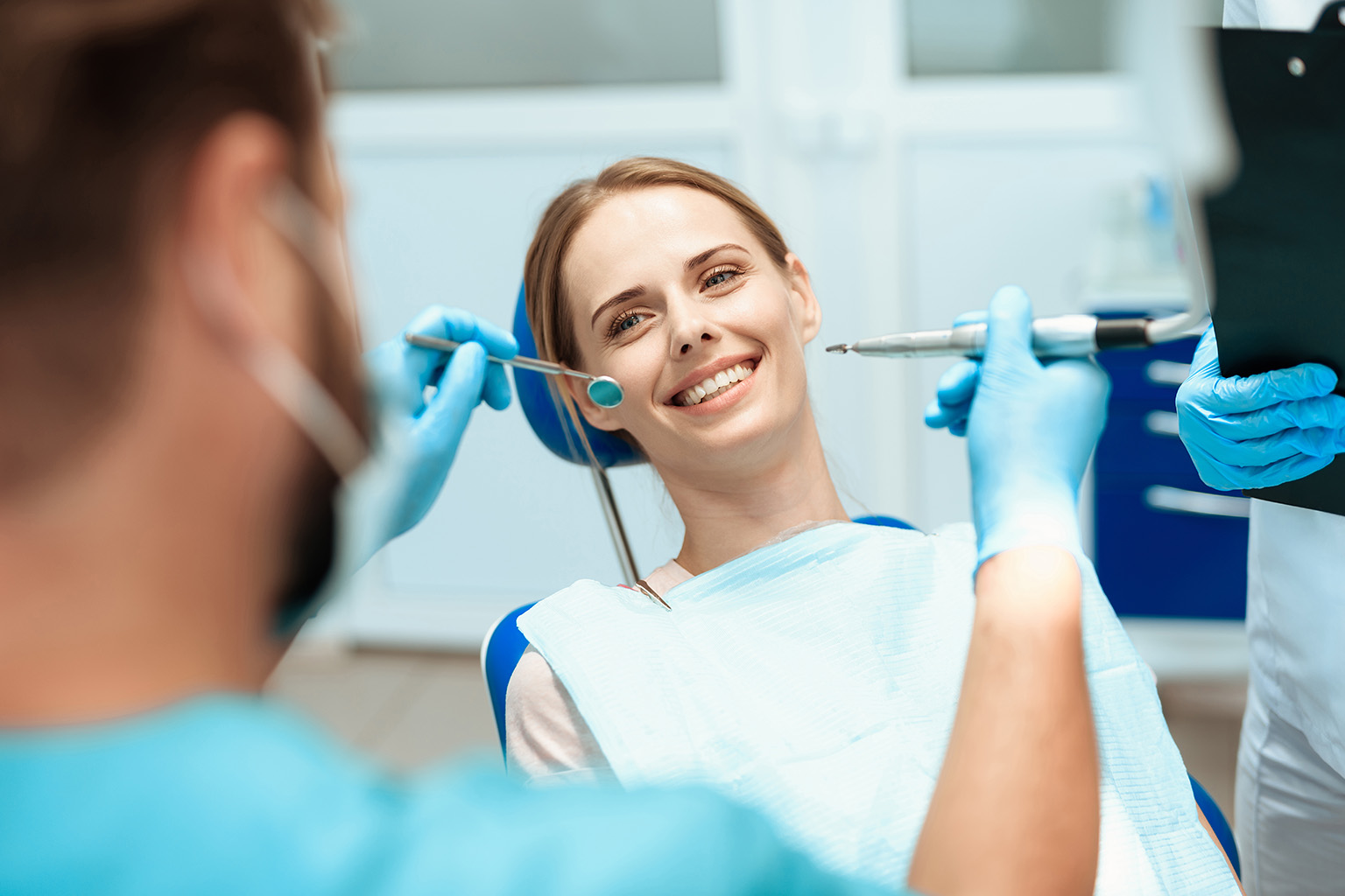 woman smiling at dentist holding dental tools