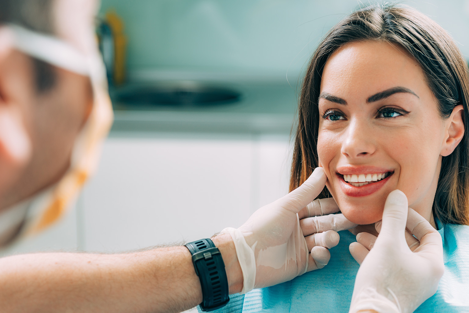 woman smiling at dentist framing her face with gloved hands