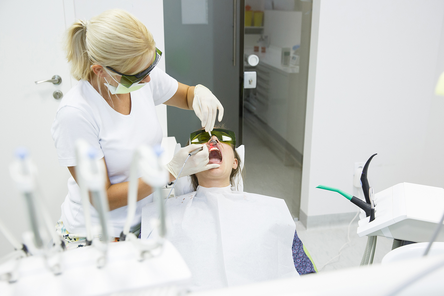 dentist using dental laser in patient's mouth in dental office