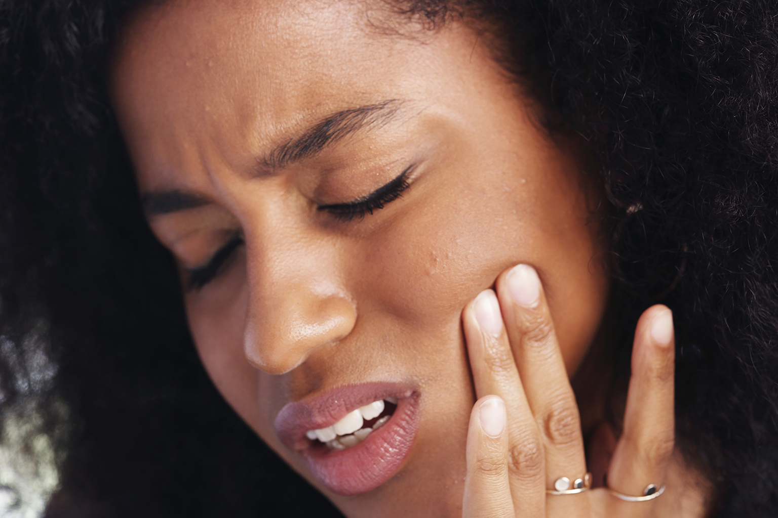 woman holding her cheek in pain