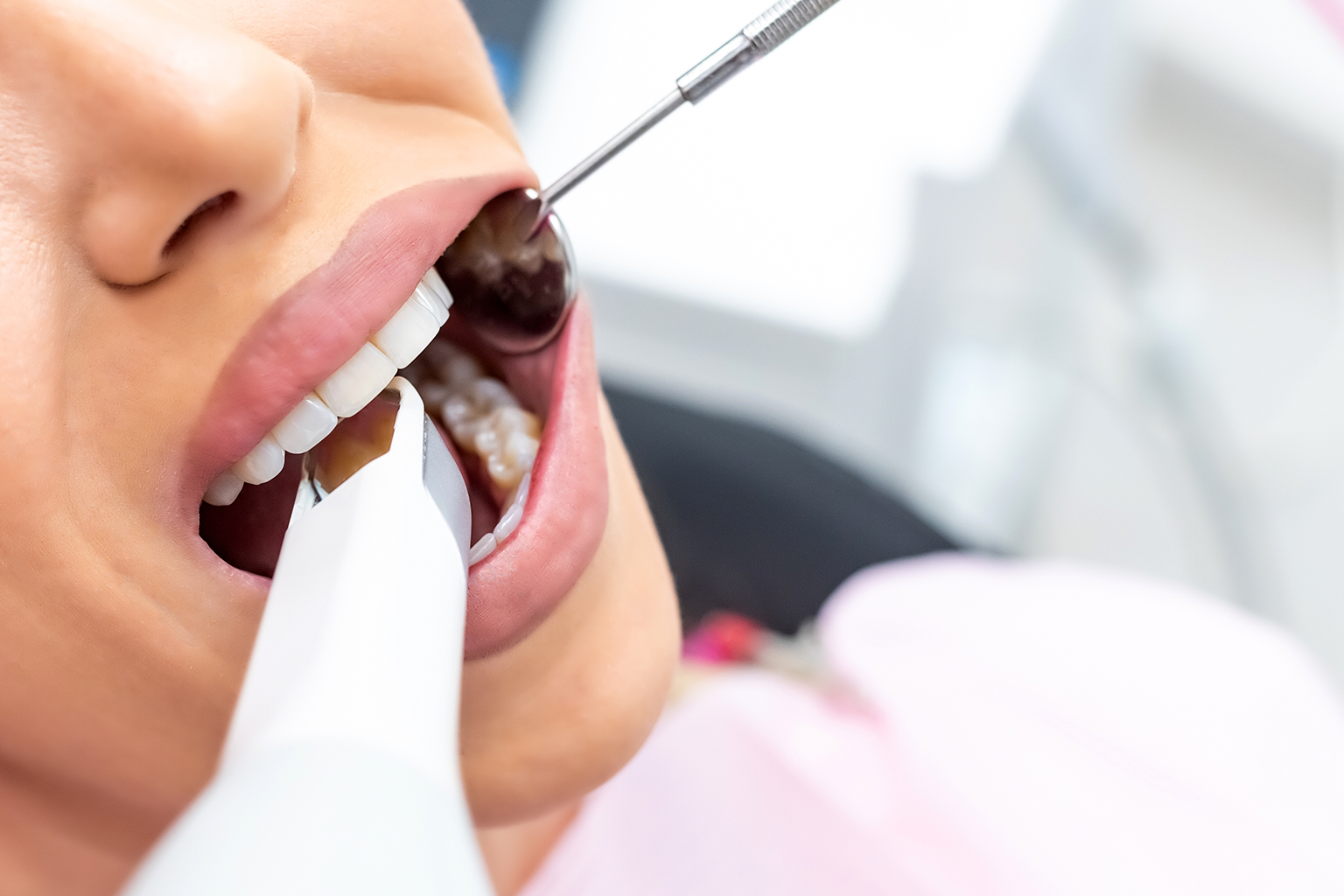 gloved hand holding dental tools in woman's mouth