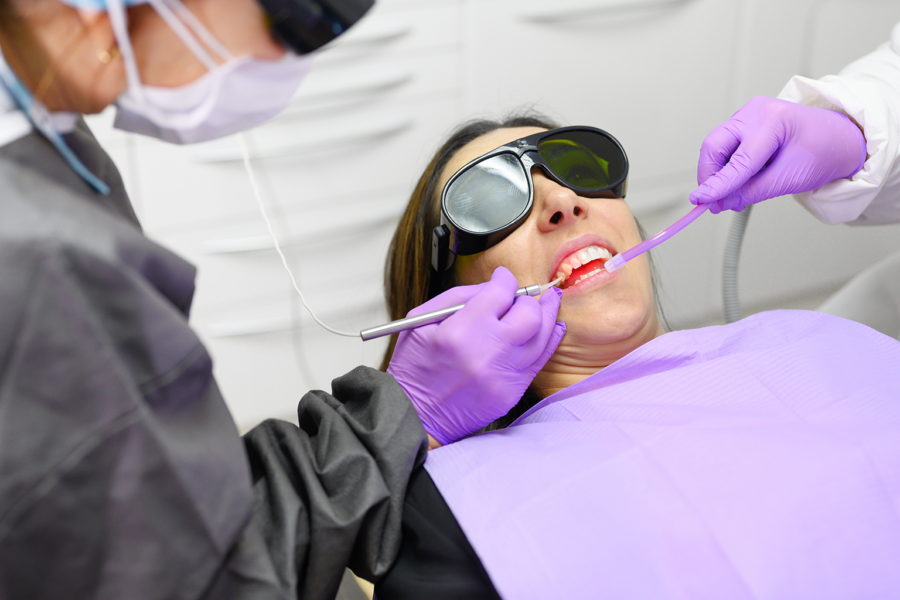 dentist using dental laser in woman's mouth