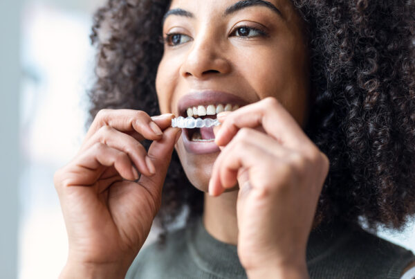 woman placing clear aligner in her mouth