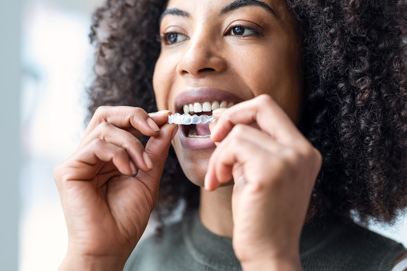 woman placing clear aligner in her mouth