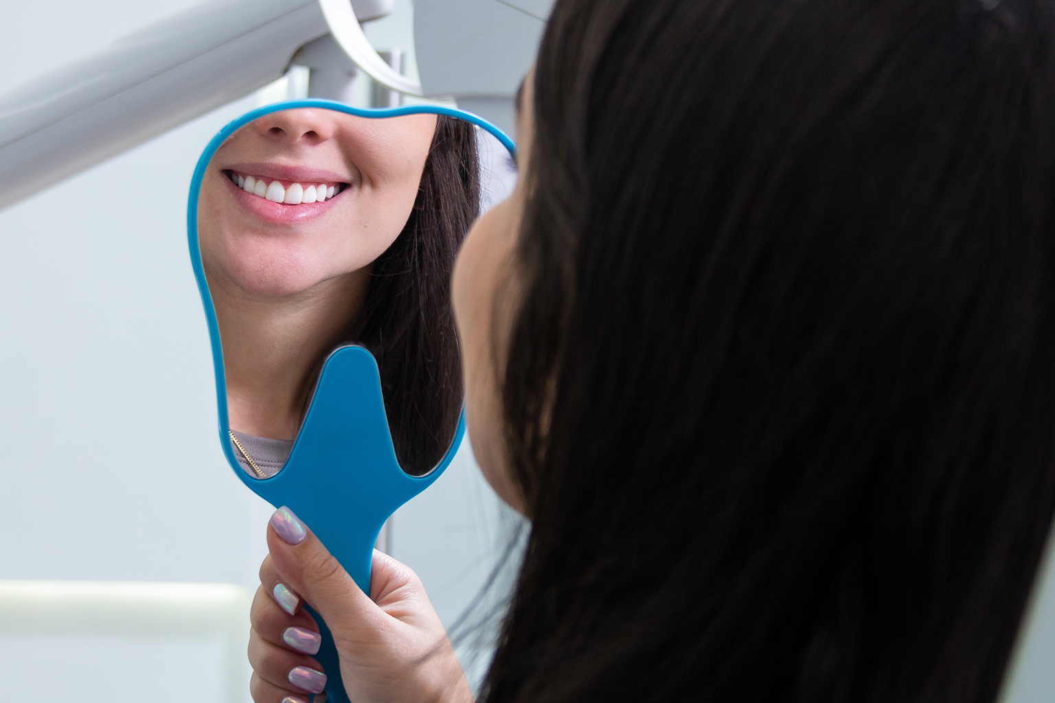 woman smiling into hand mirror