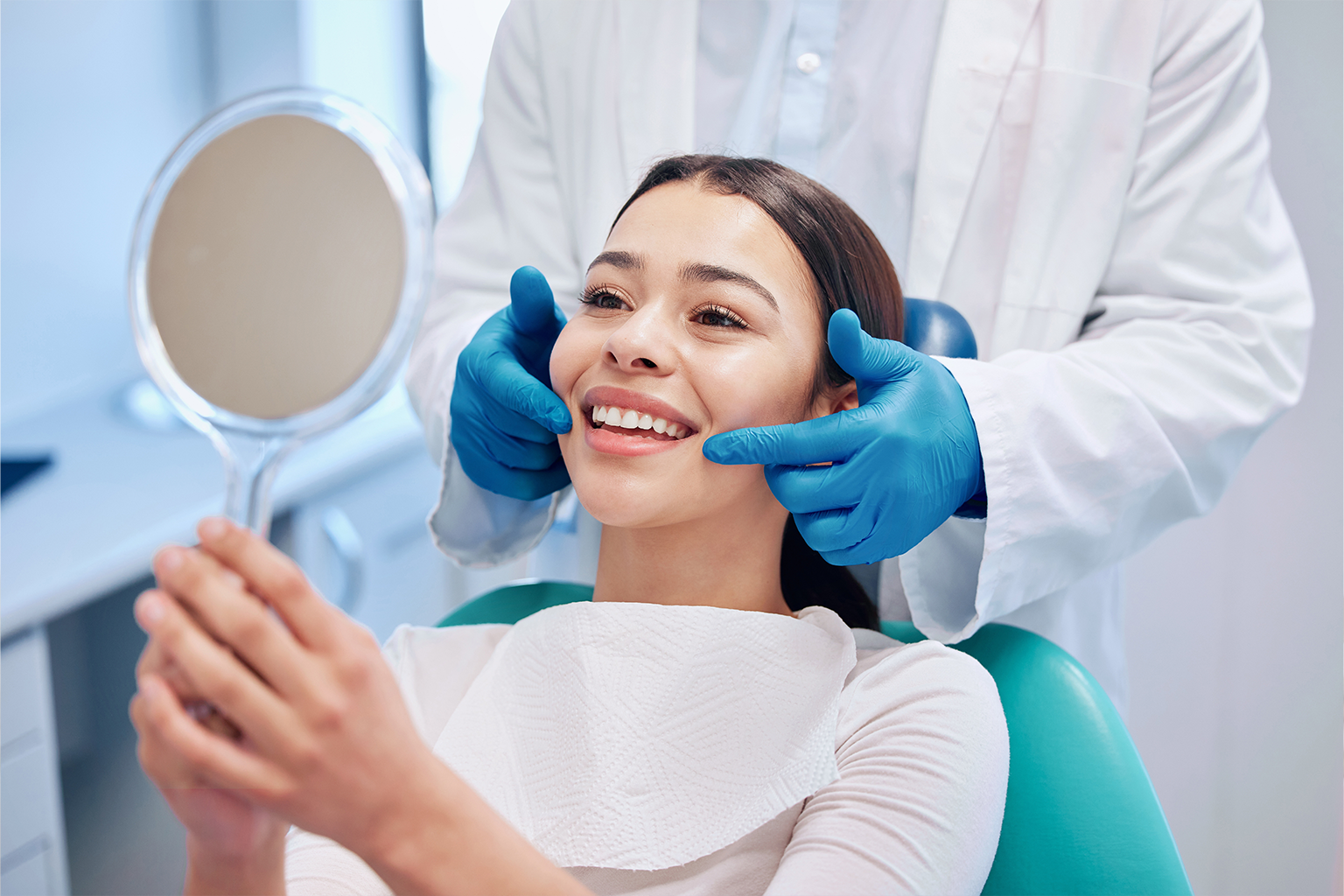 gloved hands framing the smile of woman looking into hand mirror