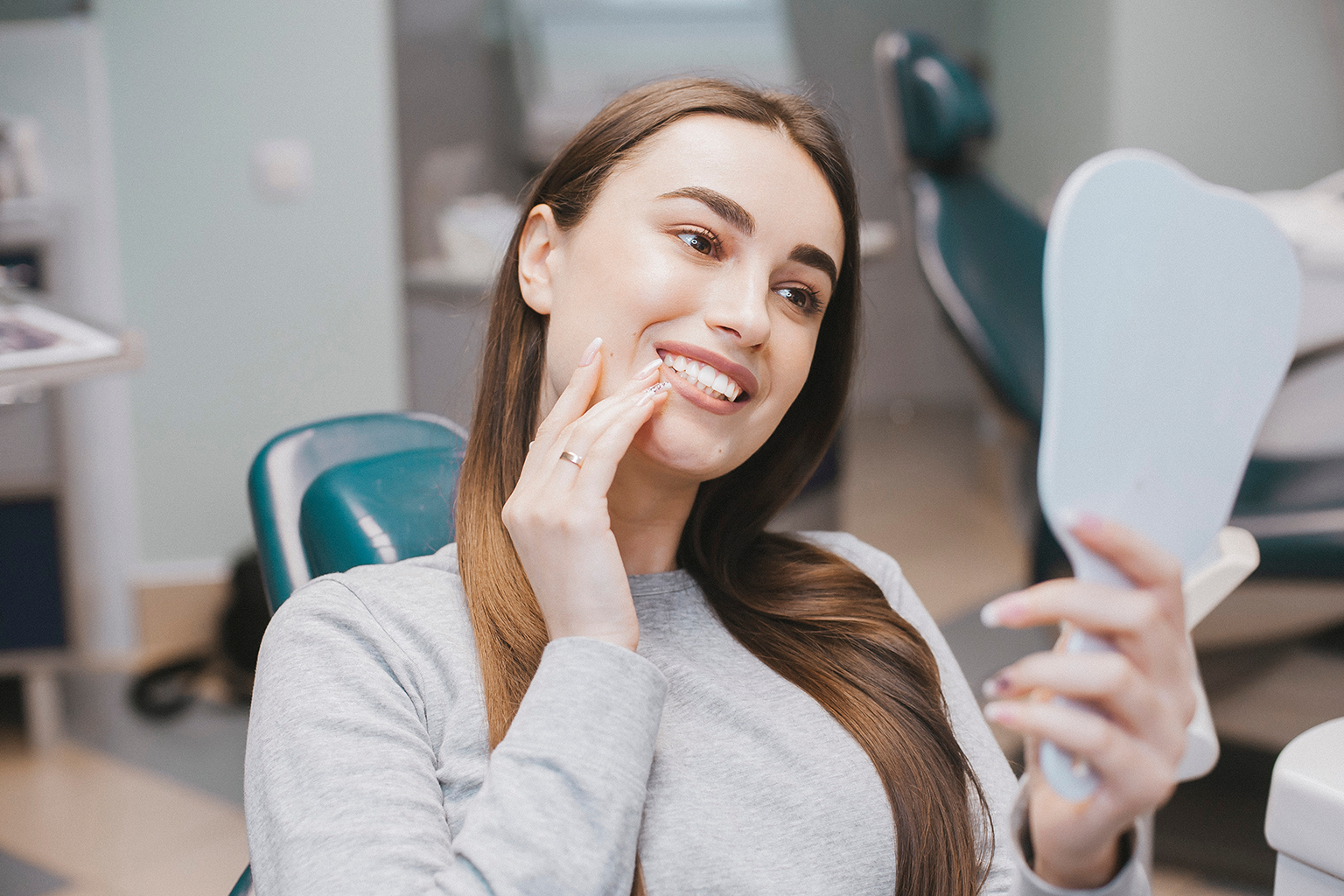 woman touching her cheek and smiling into hand mirror