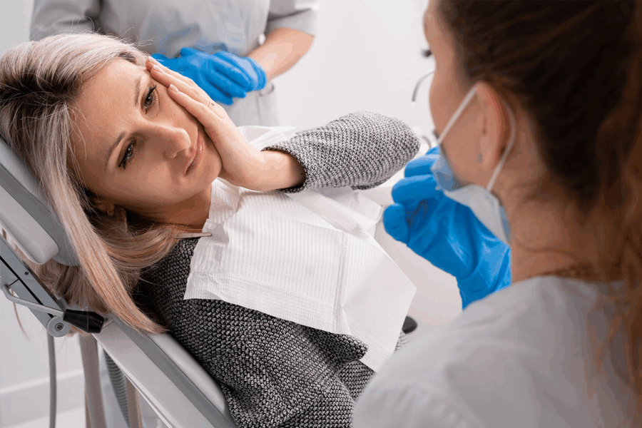 Dentist with patient holding her cheek in pain.