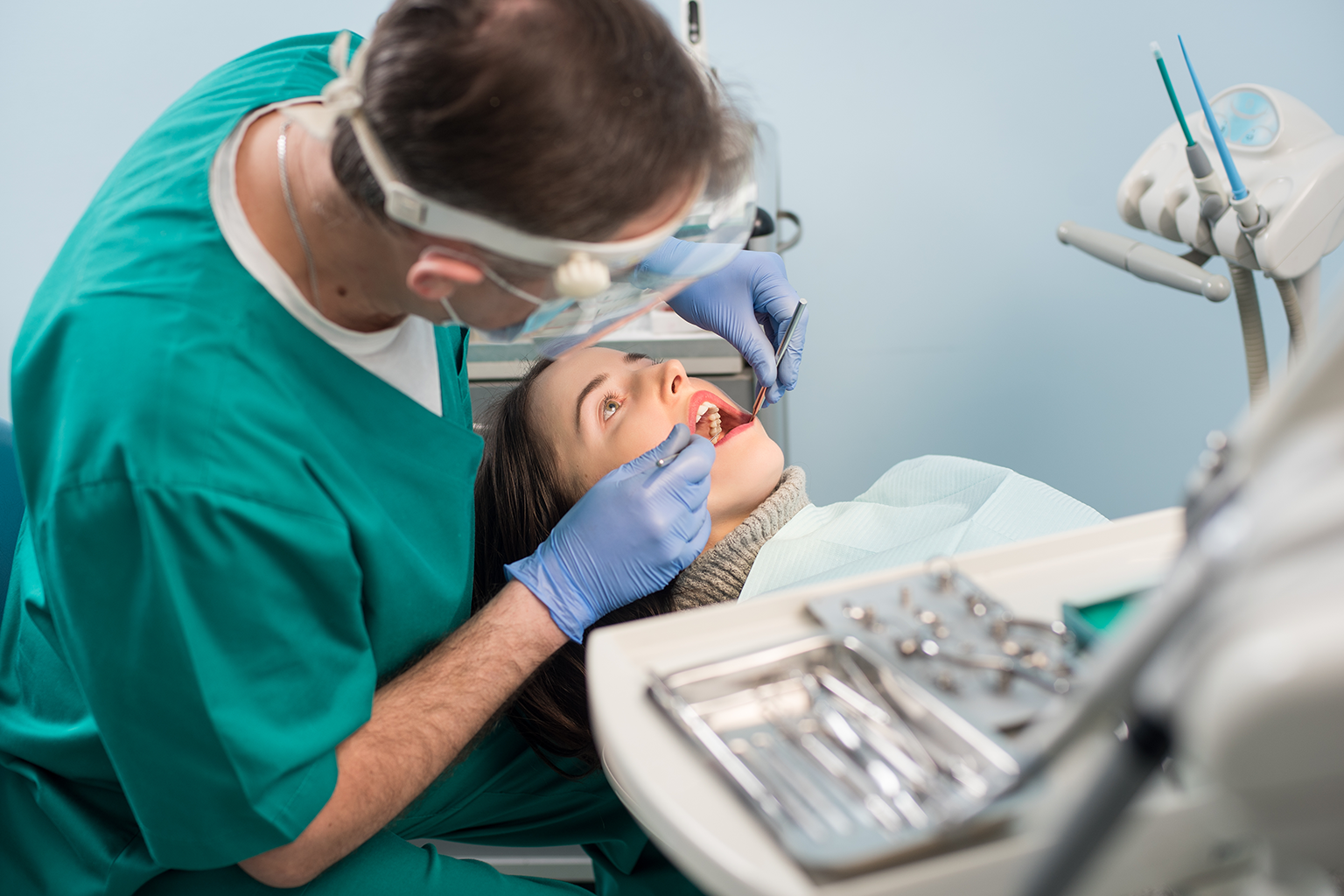 Dentist using dental tools in mouth of patient in dental chair.