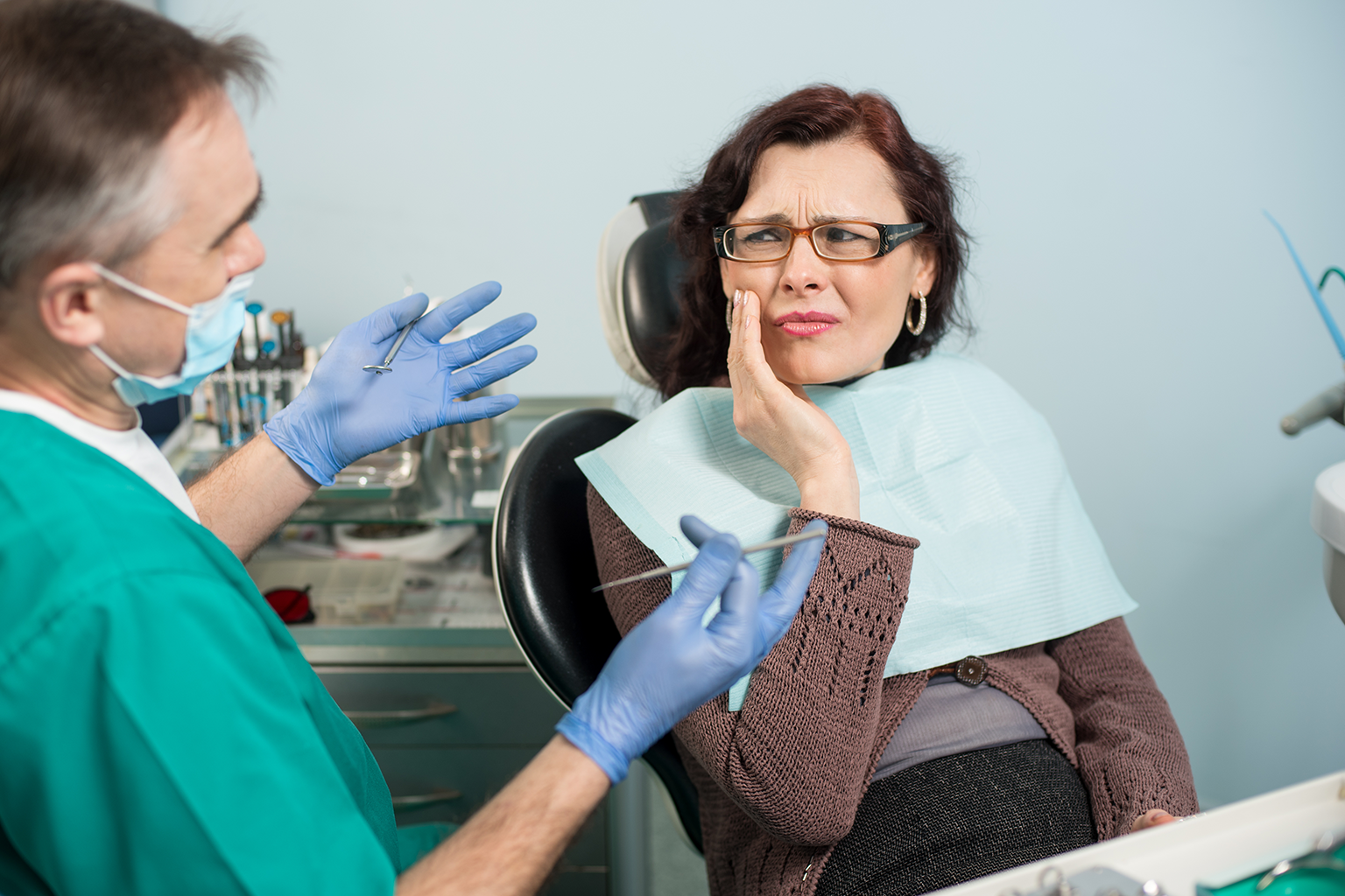 Dentist with patient holding her cheek in pain.