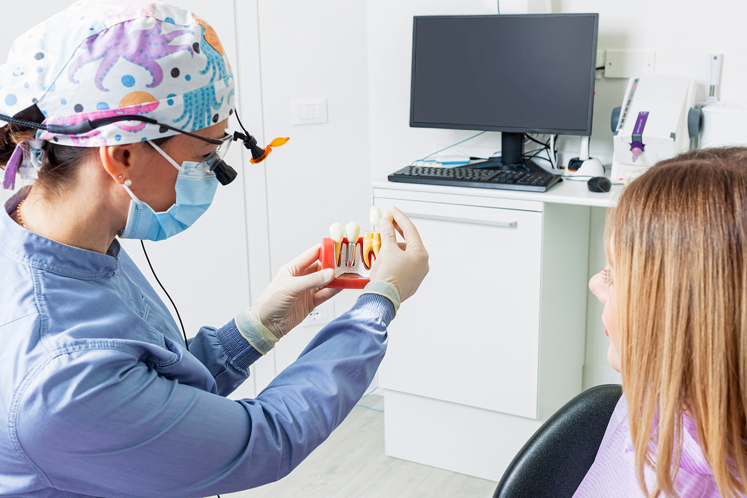 dentist showing implant to patient