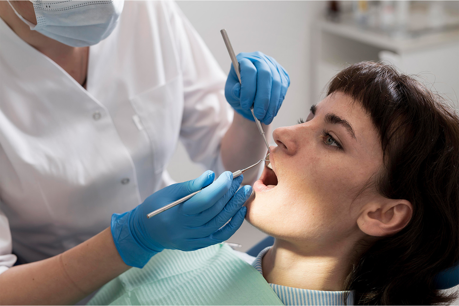 Dentist using dental tools in patient's mouth.