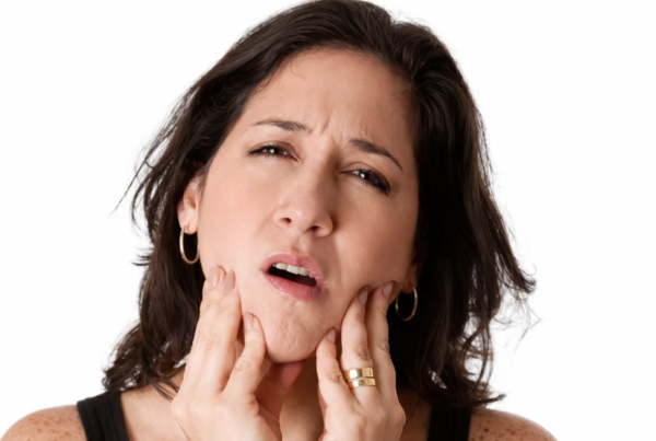 Women holding her jaw in both hands in pain.