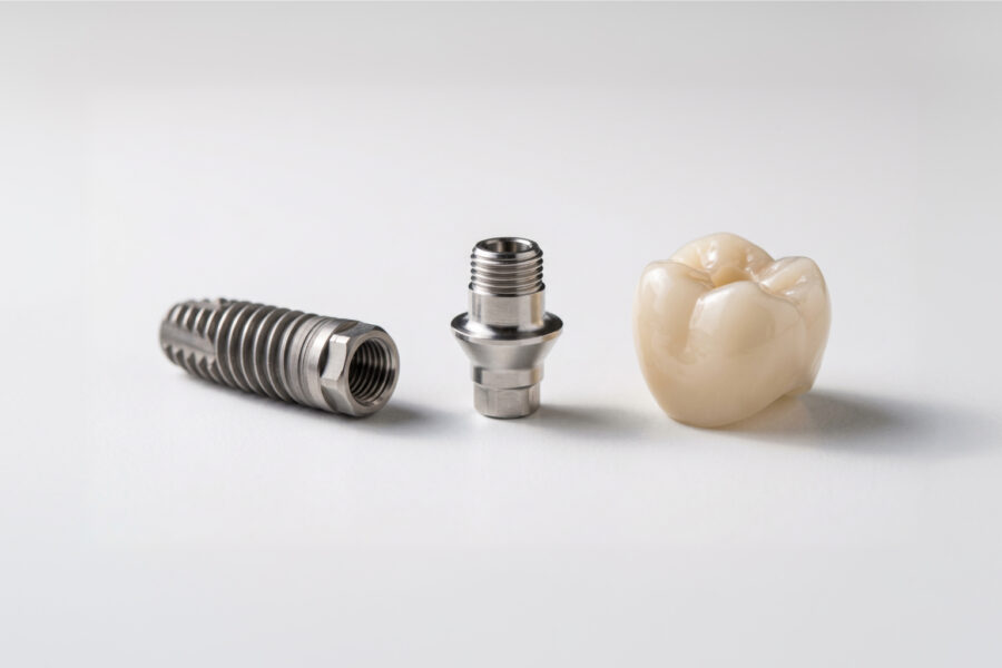 Implant, abutment, and crown on white surface.